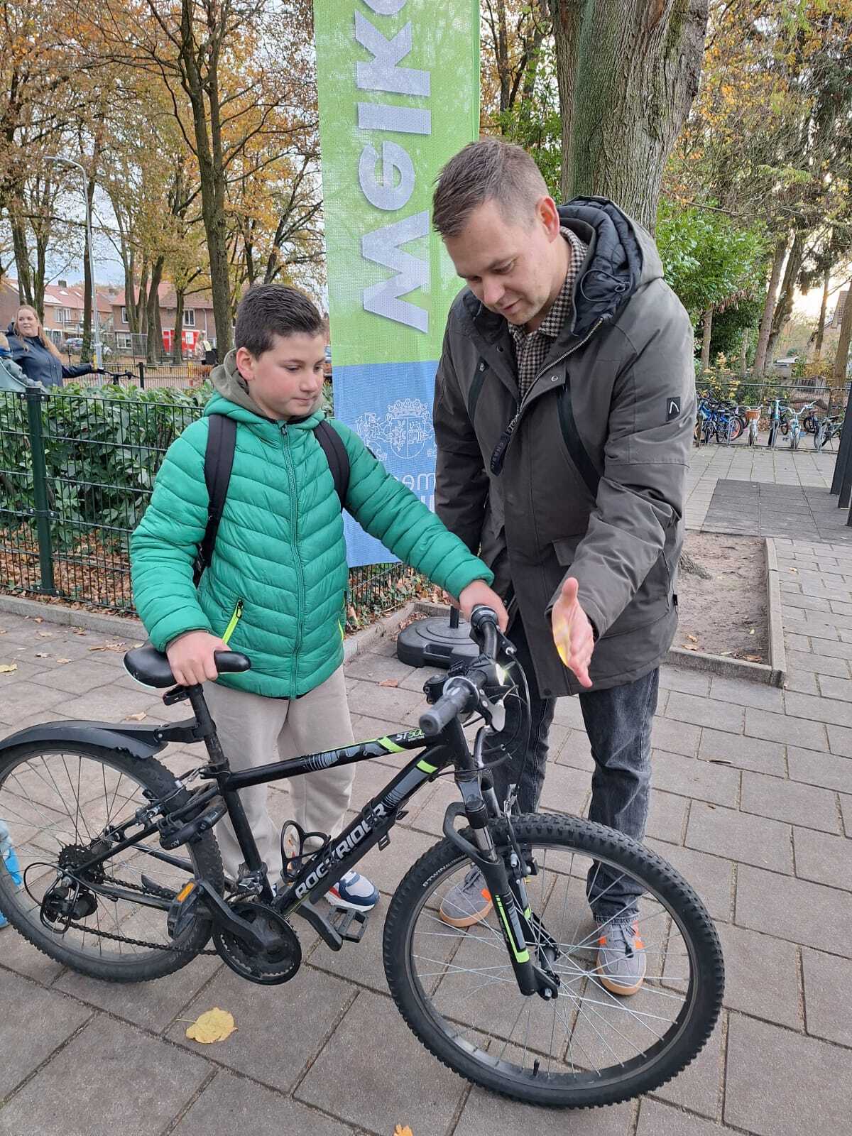 Wethouder Lennart Oosterloo kijkt of de fietsverlichting werkt bij leerlingen van basisschool De Parel