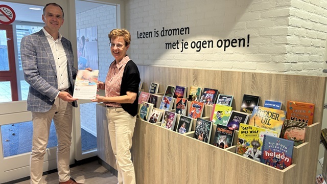 Wethouder Simonse (links) ontvangt het jaarverslag van de bibliotheek uit handen van directeur-bestuurder van de Weg