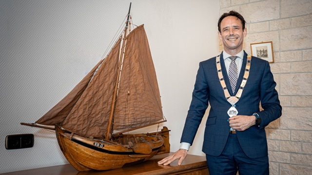 Burgemeester Harm-Jan van Schaik naast een replica van een botter
