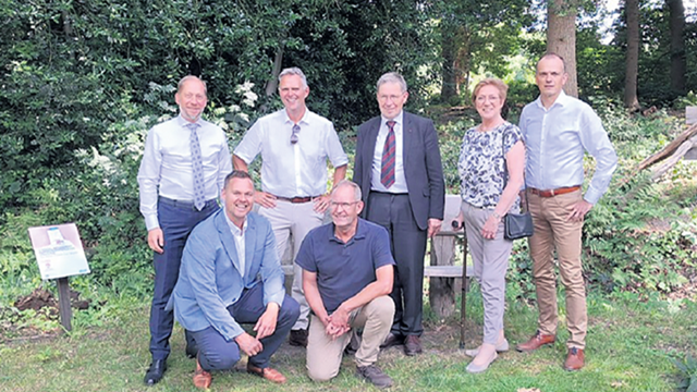 Groepsfoto van het college van burgemeester en wethouders met in het midden gedeputeerde Klaas Ruitenberg. Rechtsvoor staat Wilfred Schenk van de A.Vogel Tuinen