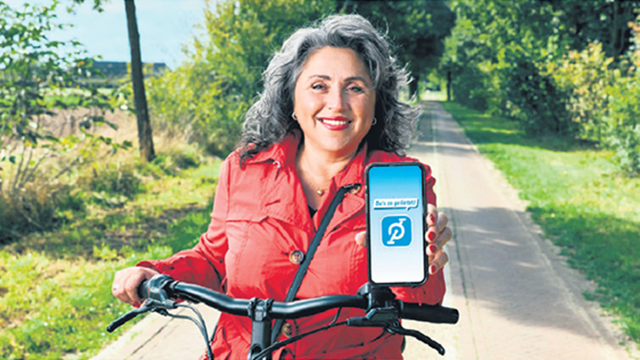 Een mevrouw doet mee aan de fietsbingo en laat de app Da's zo gefietst op haar telefoon zien